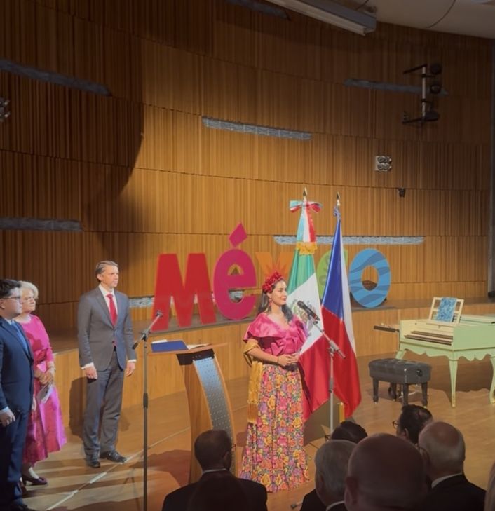 Naomi Luna en un acto conmemorativo en Praga, junto a las banderas de México y la República Checa