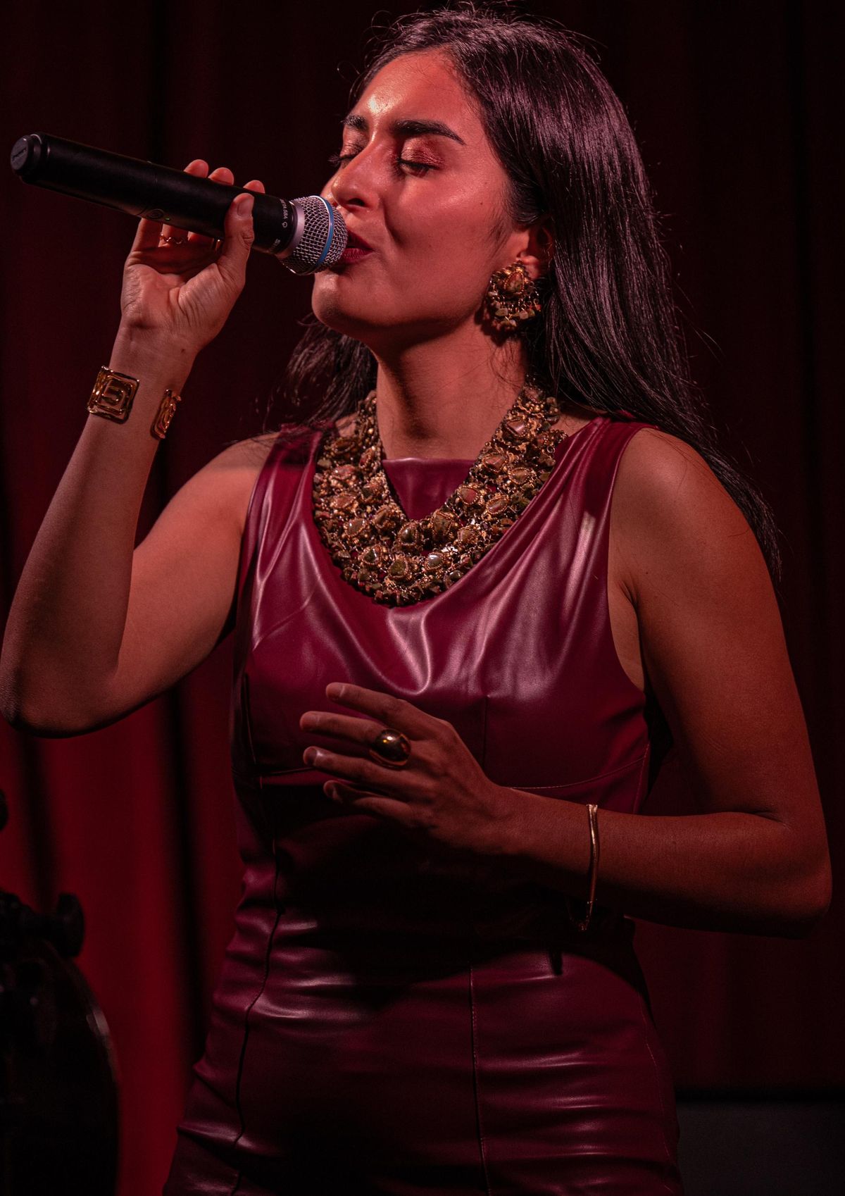 Naomi Luna cantando en concierto con vestido color vino